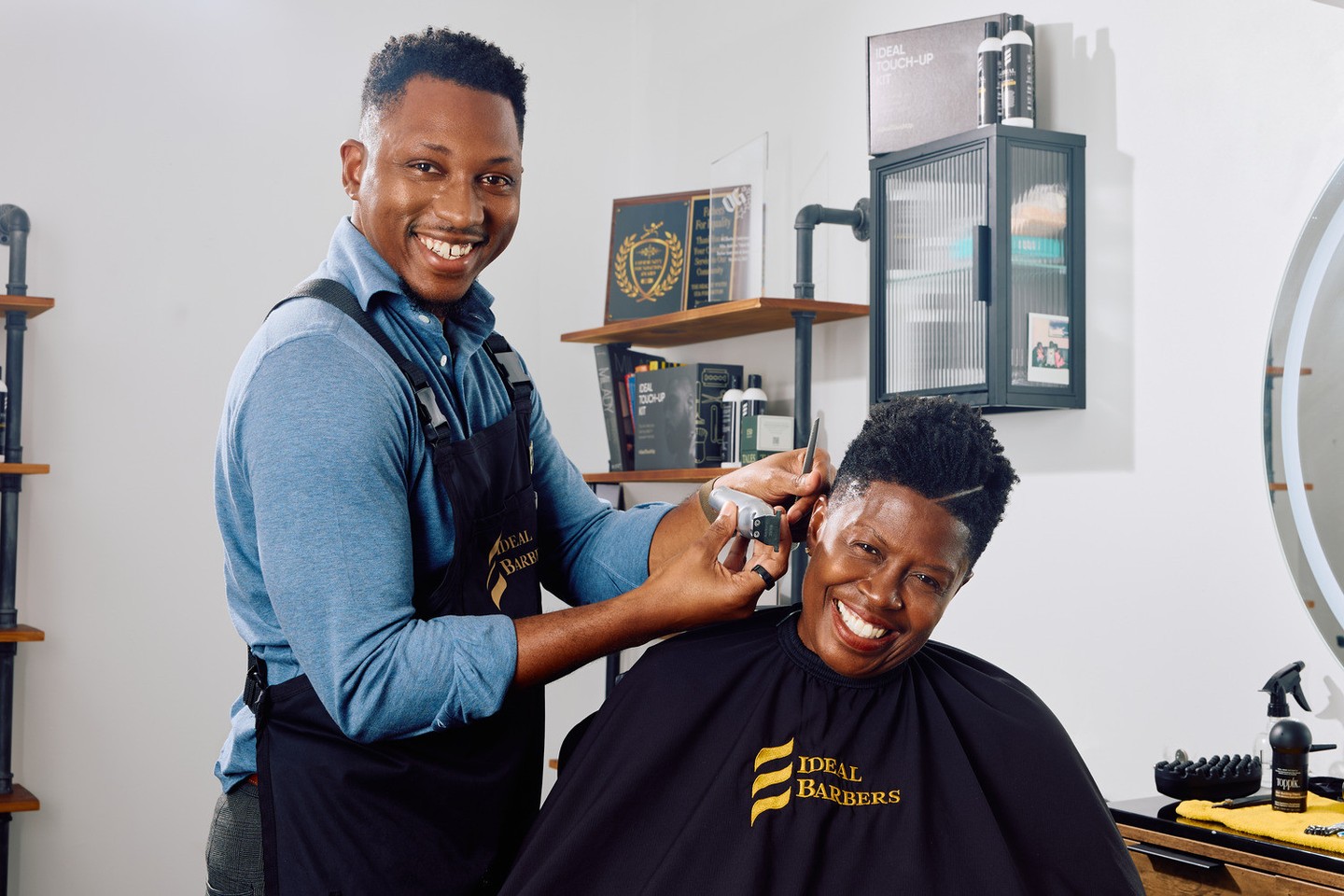 Mike giving a smiling client a haircut inside Ideal Barbers at Pittsburgh Yards.